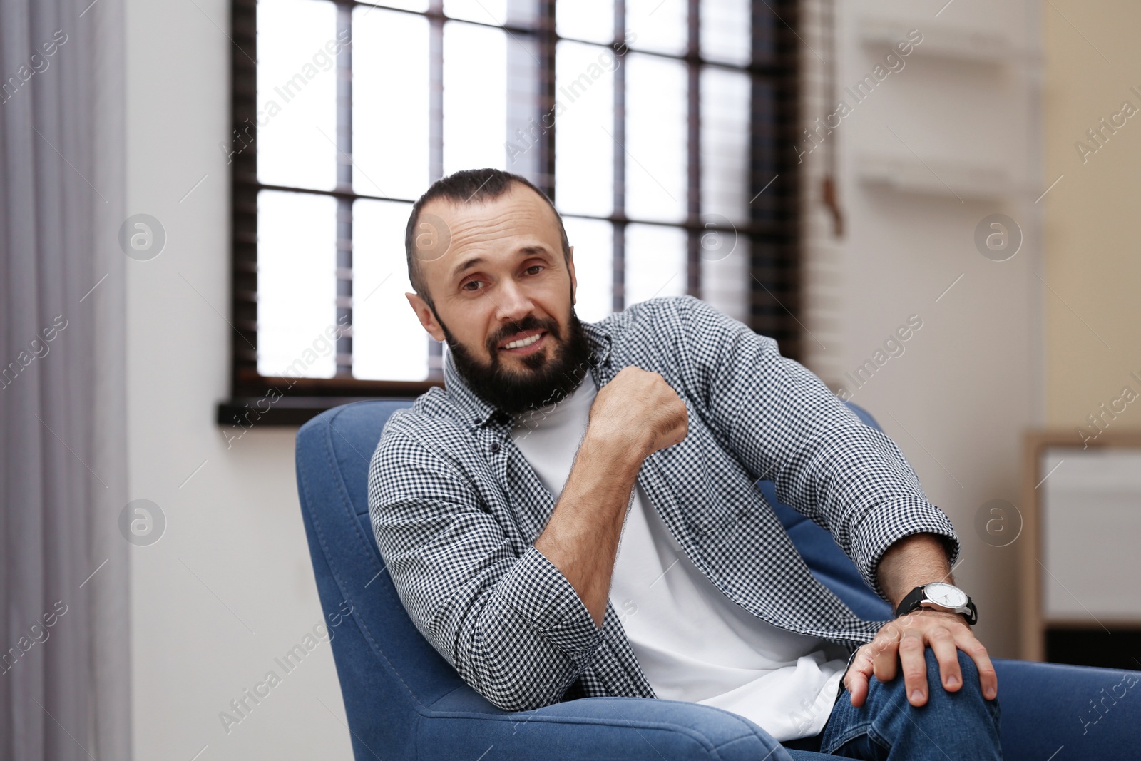 Photo of Portrait of handsome mature man sitting in armchair at home