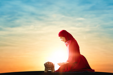 Image of Muslim woman in traditional clothes praying at sunrise. Holy month of Ramadan