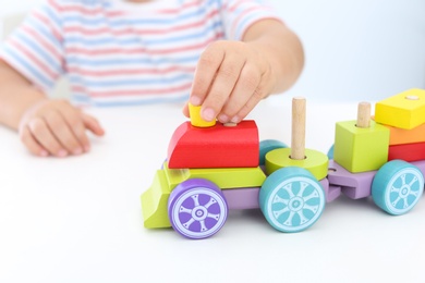 Little boy playing with toy at white table, closeup