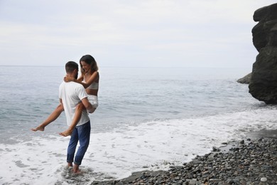 Photo of Happy young couple having fun on beach near sea. Space for text