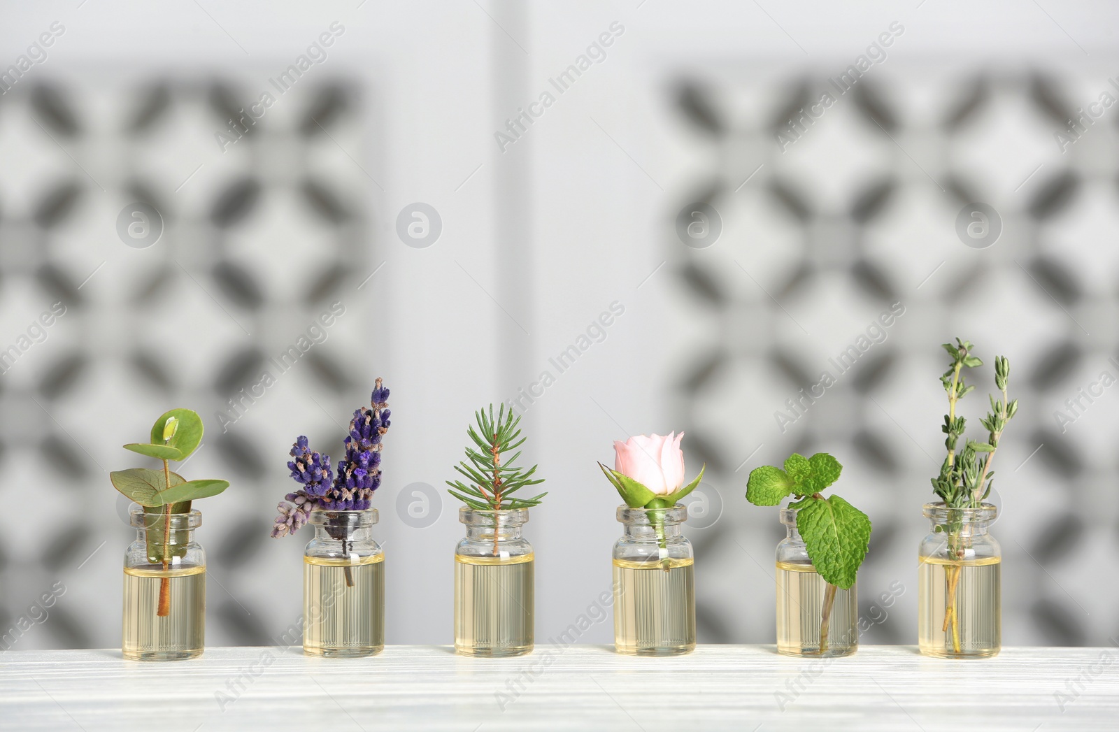 Photo of Glass bottles with different essential oils and herbs on table