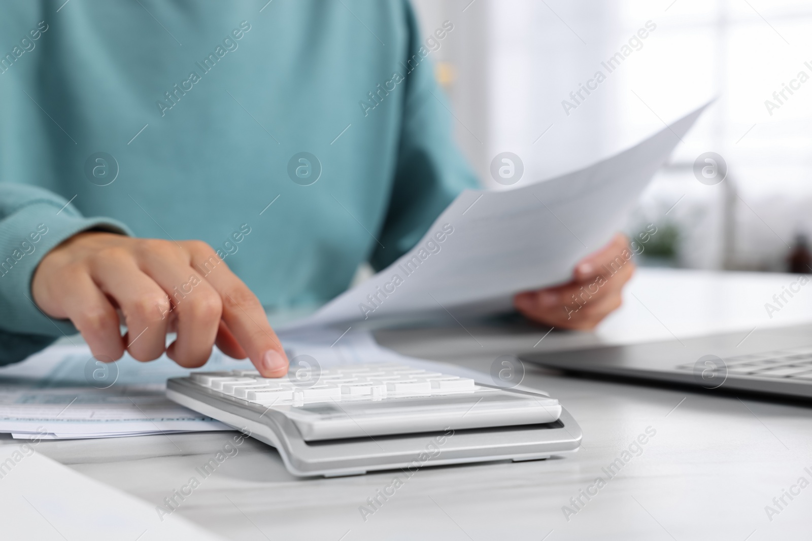 Photo of Woman calculating taxes at table indoors, closeup