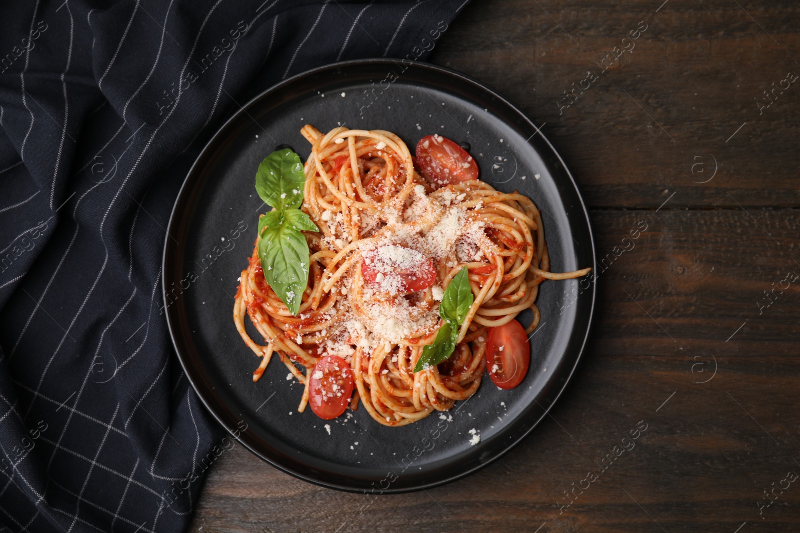 Photo of Tasty pasta with tomato sauce, cheese and basil on wooden table, top view