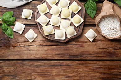 Homemade uncooked ravioli on wooden table, flat lay. Space for text