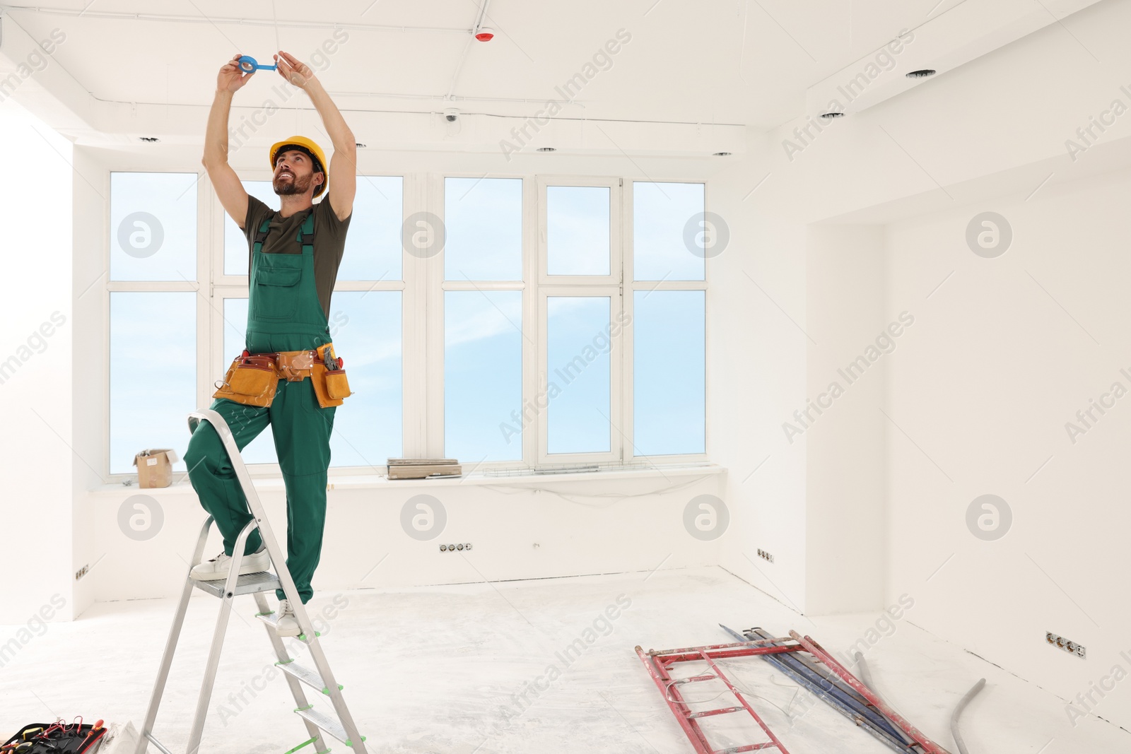 Photo of Electrician fixing wires with insulating tape indoors