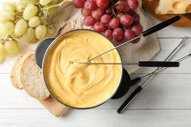 Photo of Flat lay composition with pot of delicious cheese fondue on wooden table