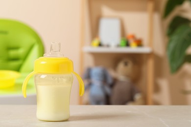 Photo of Feeding bottle with baby formula on light grey table indoors. Space for text
