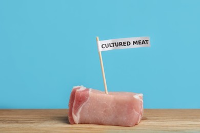 Photo of Sample of lab grown pork labeled Cultured Meat on wooden table