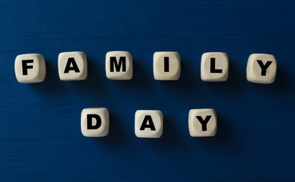 Photo of Wooden cubes with words Family Day on blue table, flat lay