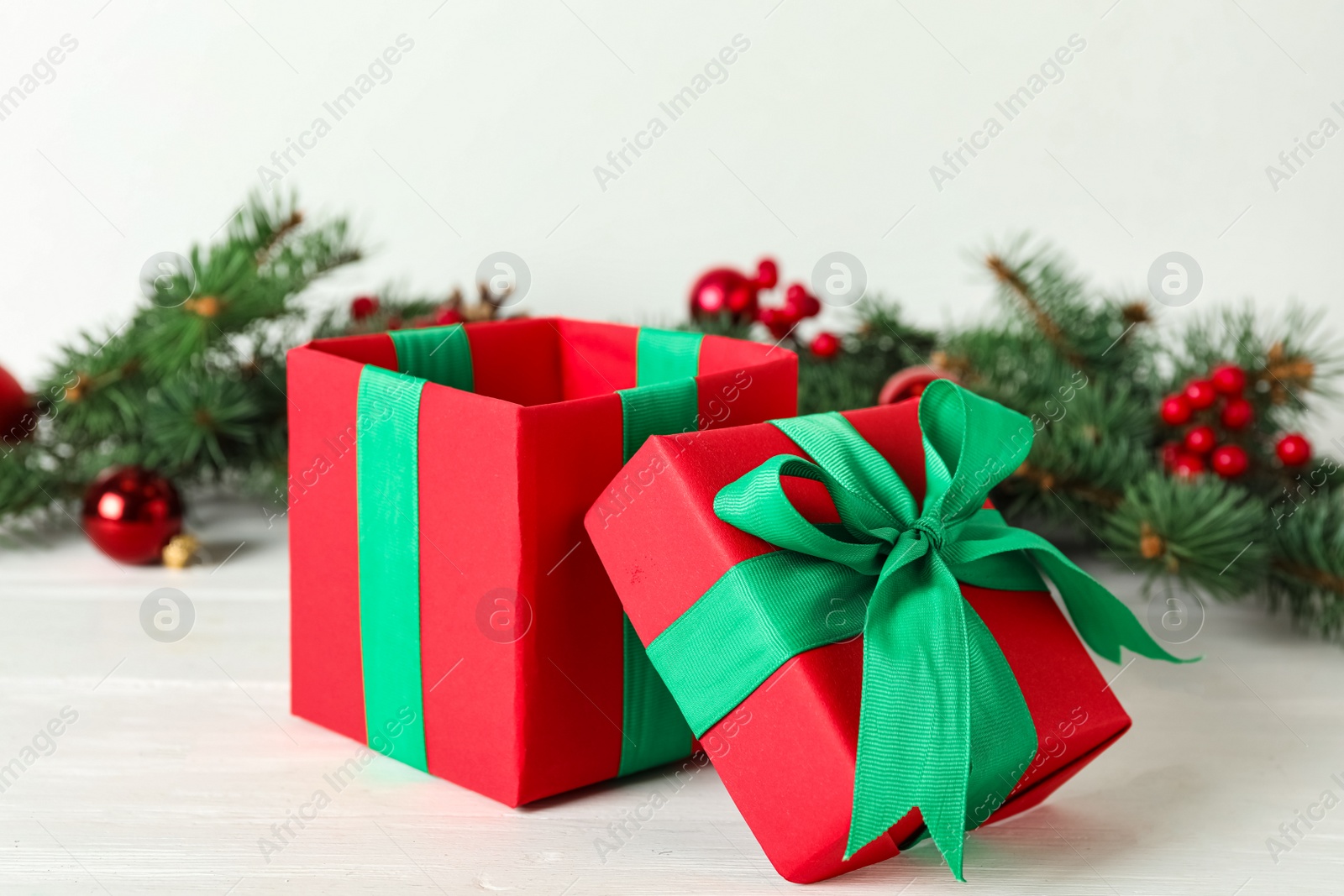 Photo of Red Christmas gift box with green bow on white wooden table