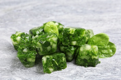 Ice cubes with cucumber slices and herbs on grey table