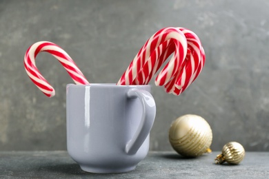 Photo of Many sweet candy canes in cup on grey table. Traditional Christmas treat