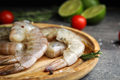 Photo of Fresh raw shrimps with rosemary on wooden board, closeup