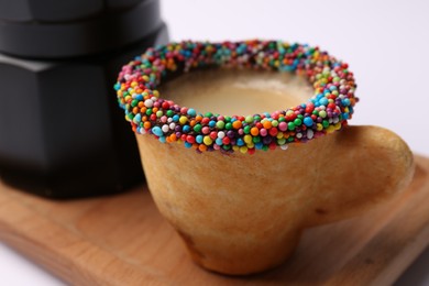 Delicious edible biscuit cup decorated with sprinkles on white background, closeup
