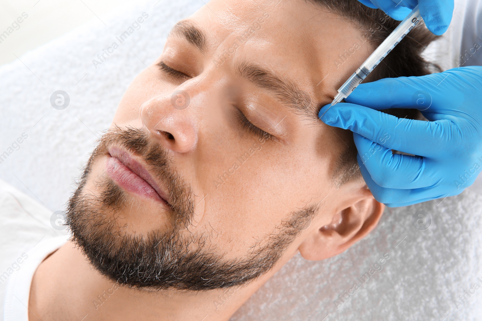 Photo of Man getting facial injection in clinic. Cosmetic surgery concept