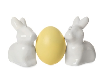 Cute ceramic Easter bunnies and dyed egg on white background