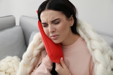 Woman using hot water bottle to relieve pain at home