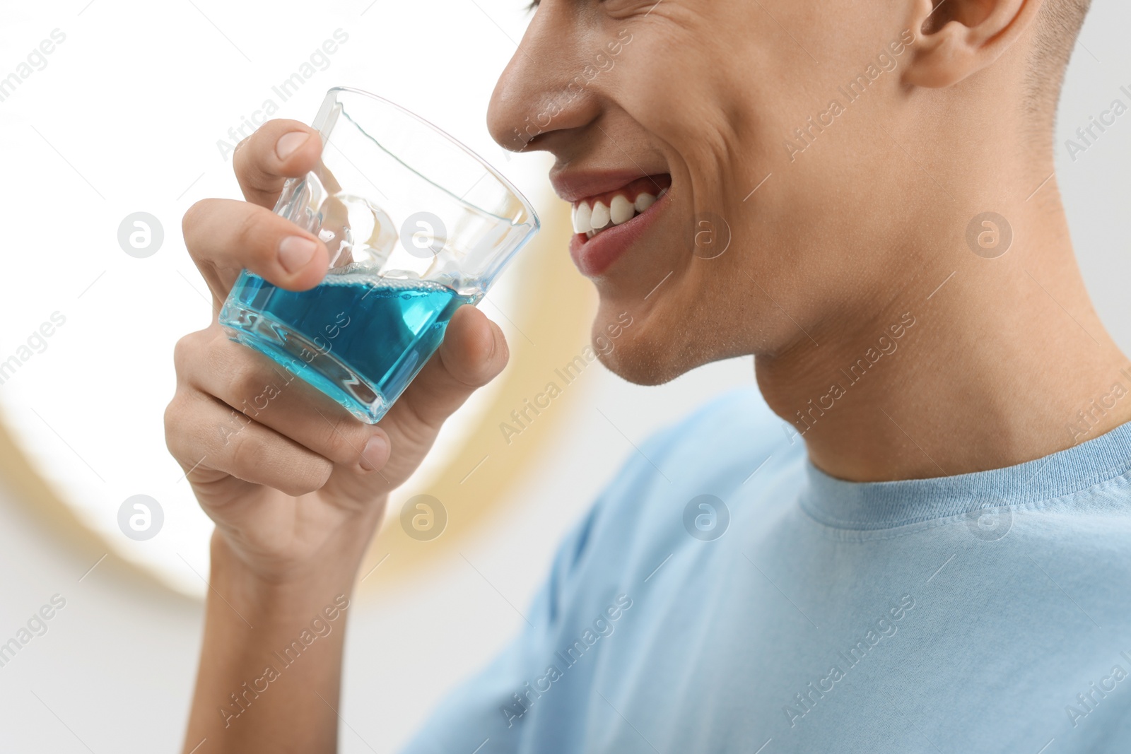 Photo of Young man using mouthwash indoors, closeup view