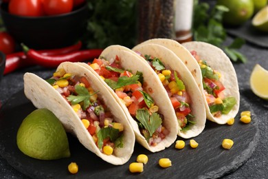 Photo of Tasty tacos with vegetables on black table, closeup