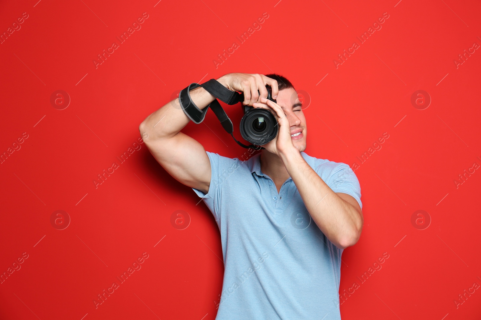 Photo of Young professional photographer taking picture on red background