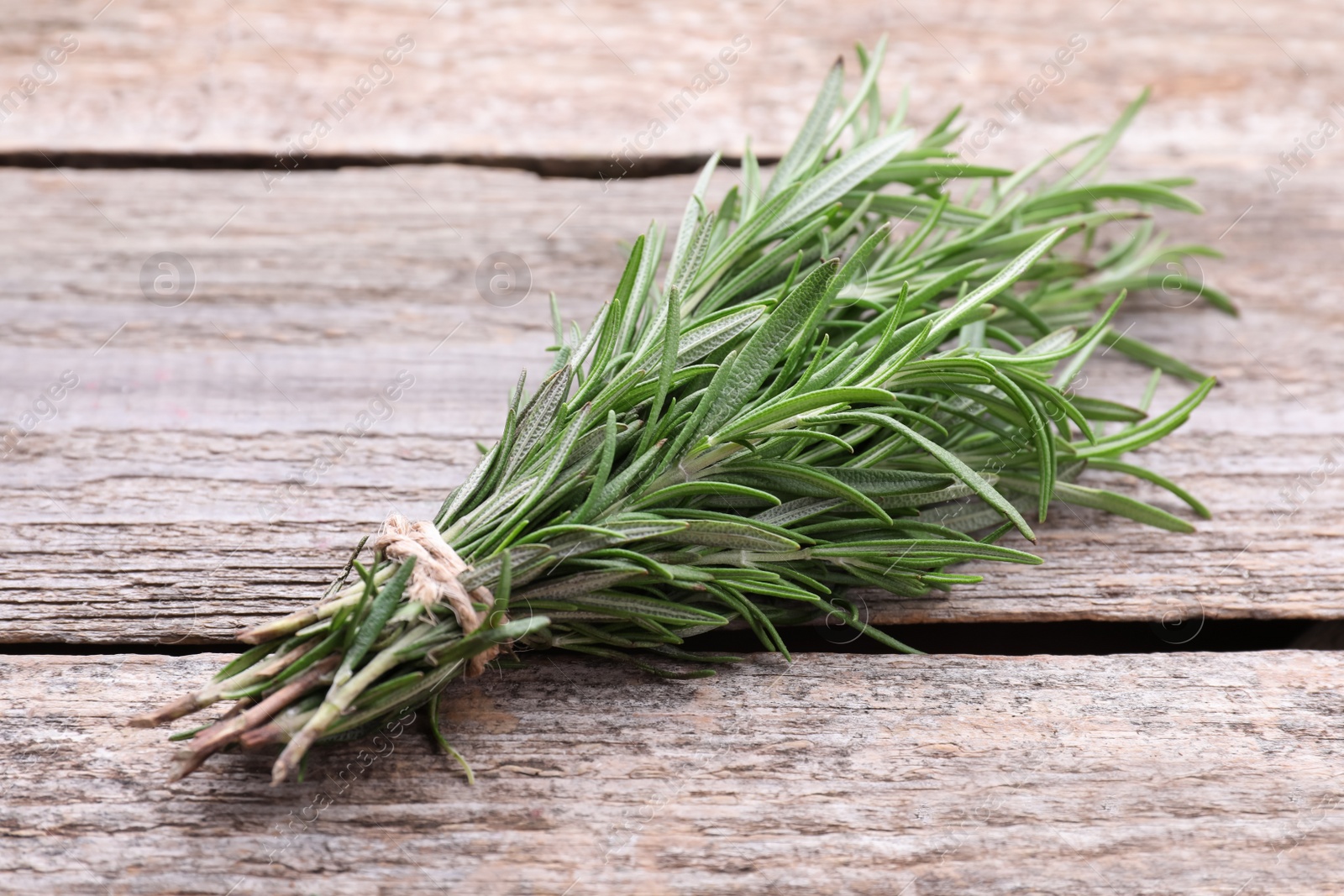 Photo of Bunch of fresh rosemary on wooden table, closeup