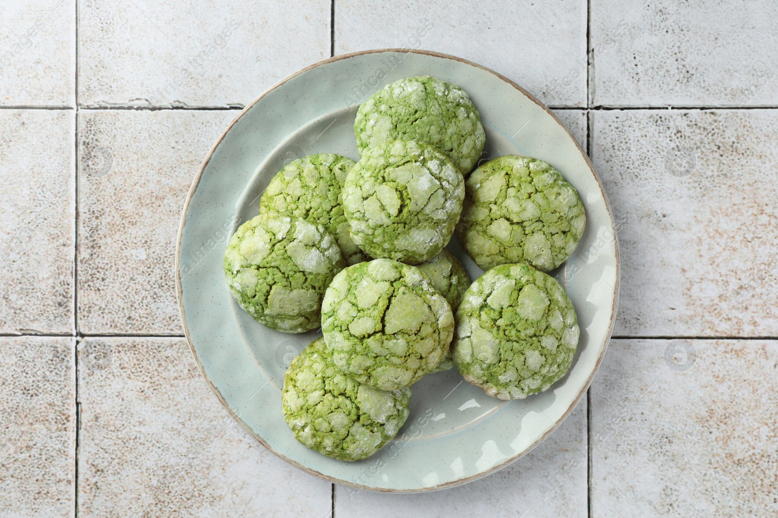 Photo of Plate with tasty matcha cookies on tiled table, top view