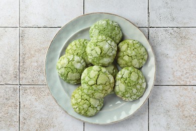 Plate with tasty matcha cookies on tiled table, top view