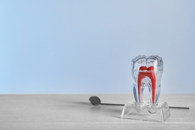Photo of Tooth model and dentist mirror on table. Space for text