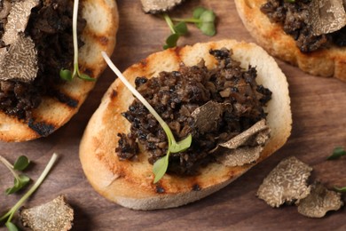 Photo of Delicious bruschettas with truffle sauce and microgreens on serving board, closeup