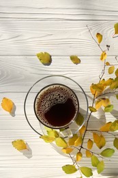 Cup of hot drink and leaves on white wooden table, flat lay. Cozy autumn atmosphere