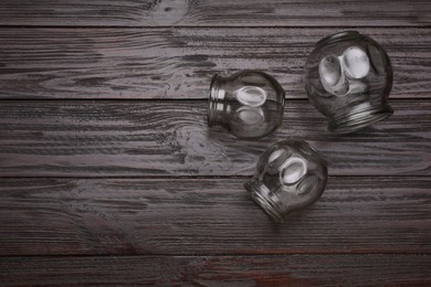 Photo of Cupping therapy. Glass cups on wooden table, flat lay with space for text