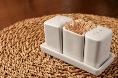 Photo of Holder with salt, pepper and toothpicks on wicker mat. Space for text