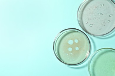 Petri dishes with liquids on turquoise background, flat lay. Space for text