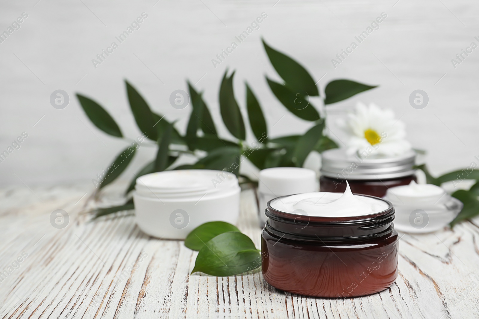 Photo of Composition with body cream in jars on light background