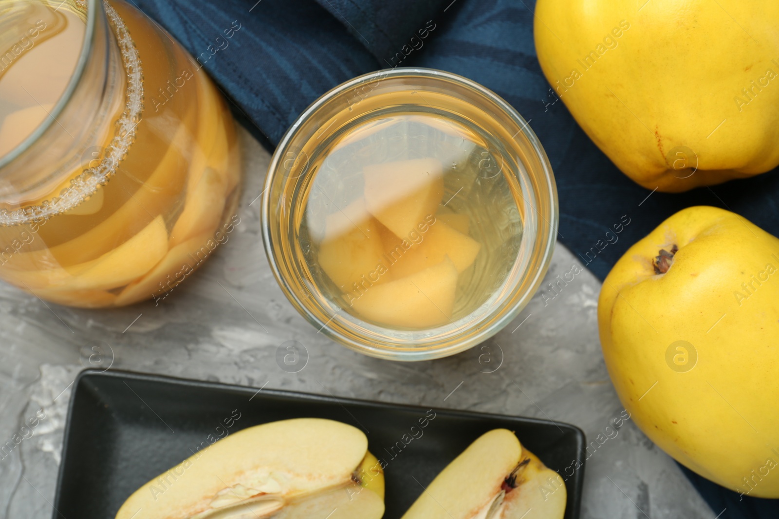 Photo of Delicious quince drink and fresh fruits on grey table, flat lay