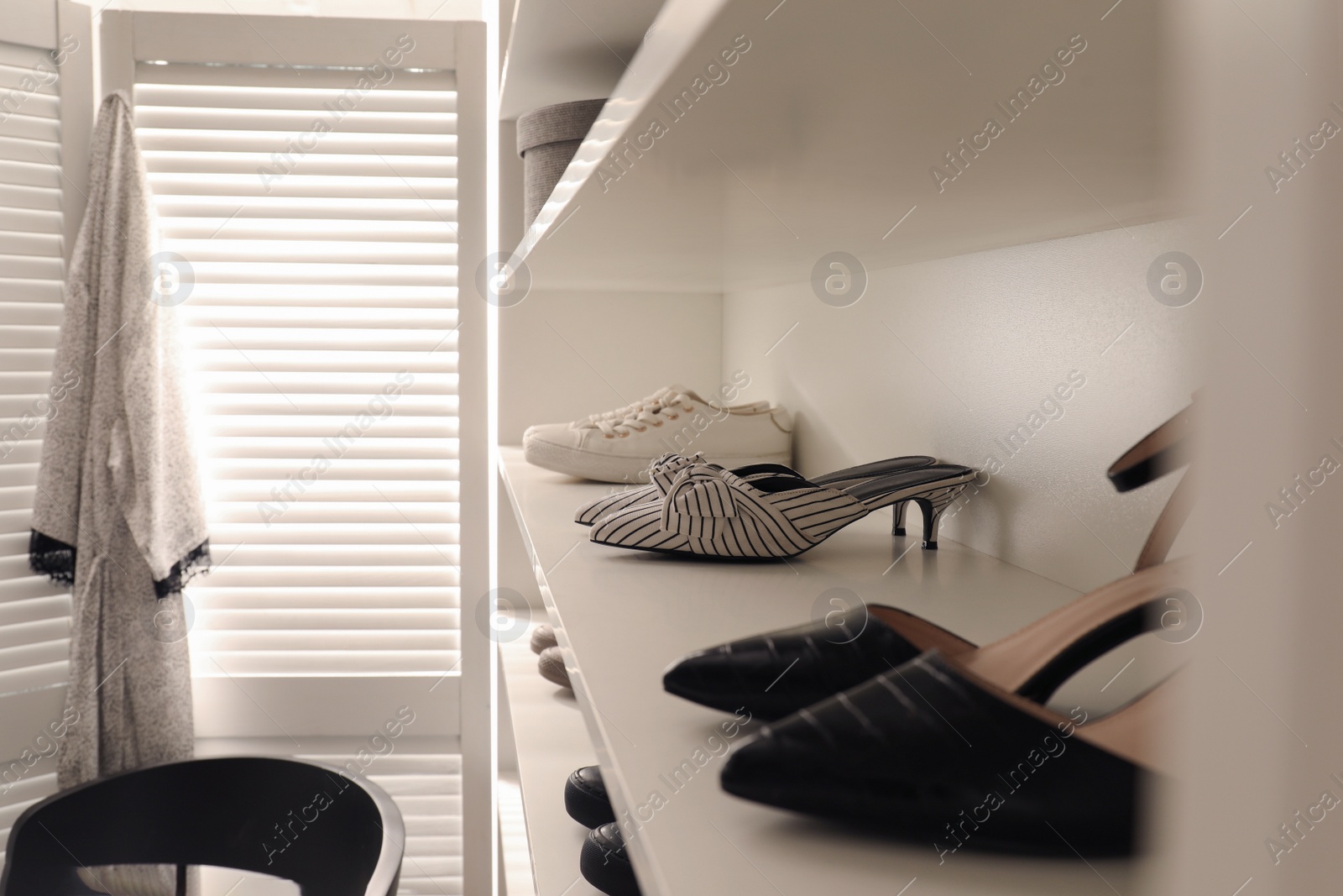 Photo of Storage rack with stylish women's shoes indoors, closeup