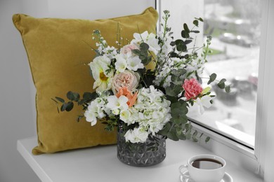 Bouquet of beautiful flowers and coffee on windowsill