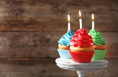 Photo of Delicious birthday cupcakes with candles on dessert stand