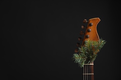 Photo of Guitar with fir tree twig on black background. Christmas music concept