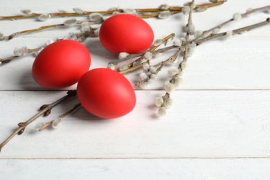 Red dyed Easter eggs and pussy willow on wooden table, space for text