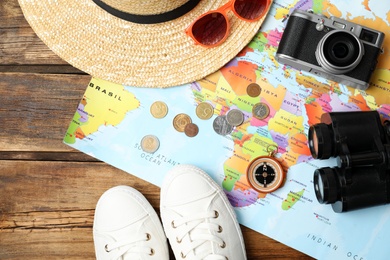 Flat lay composition with world map and different travel accessories on wooden table. Planning summer vacation trip