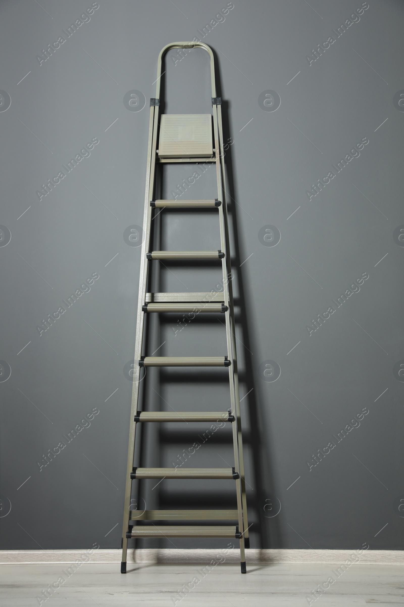 Photo of Modern metal step ladder near grey wall