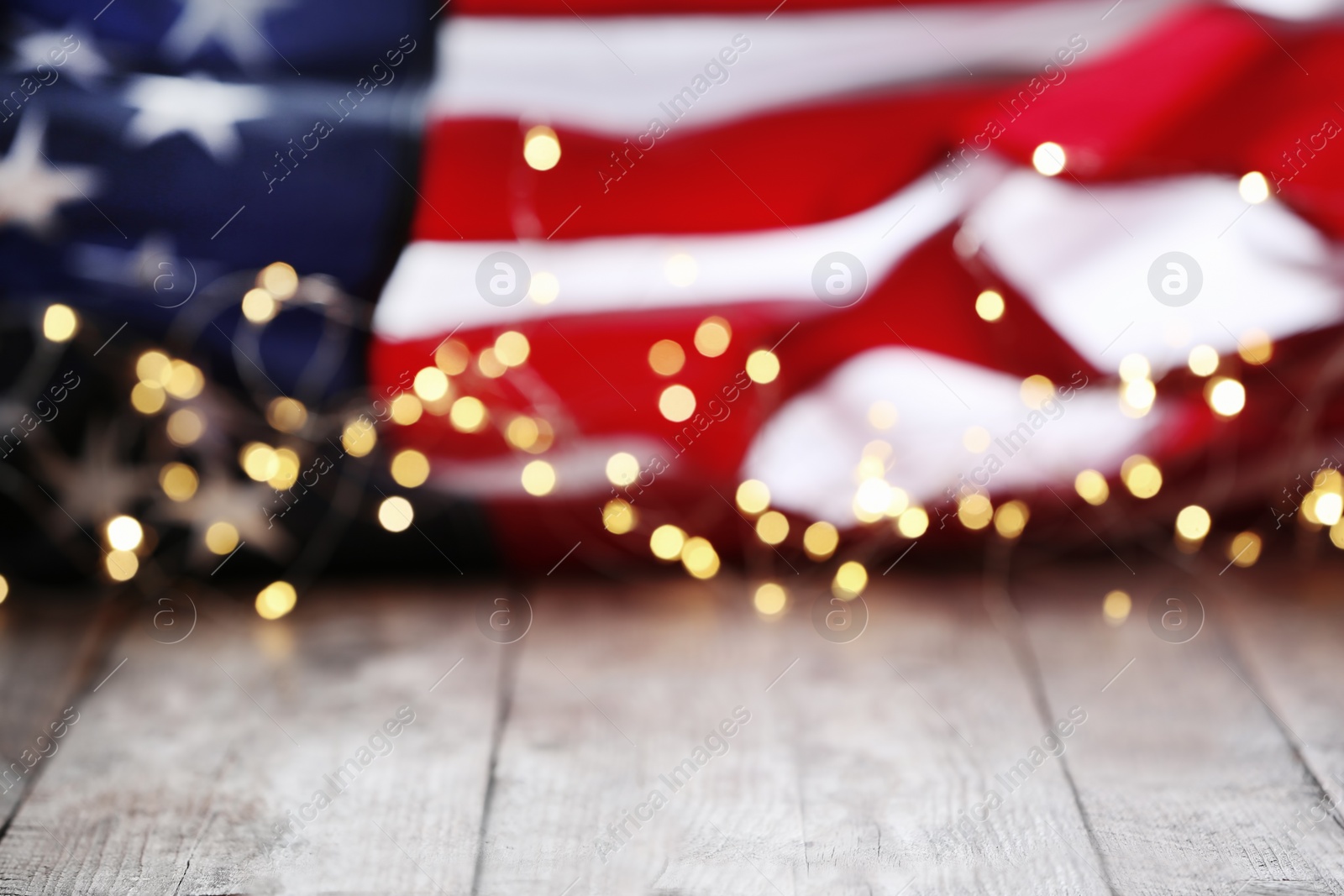 Photo of Blurred lights and American flag on wooden table. Mockup for design