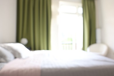 Photo of Blurred view of large bed near window in room