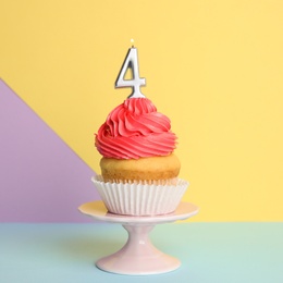 Photo of Birthday cupcake with number four candle on stand against color background