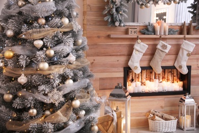 Photo of Christmas tree near decorative fireplace in room, closeup view. Festive interior