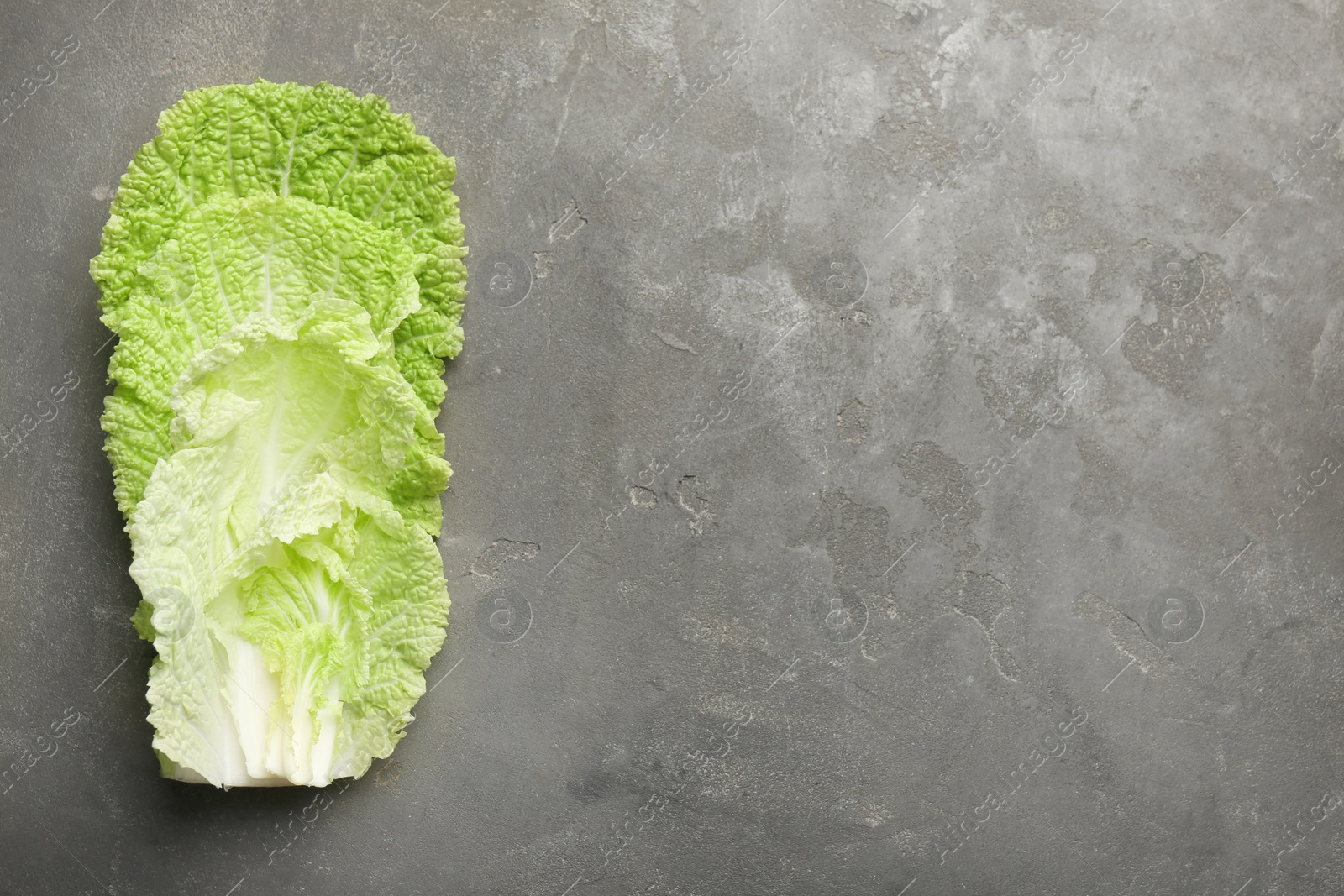 Photo of Fresh Chinese cabbage leaves on gray textured table, top view. Space for text