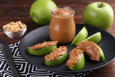 Slices of fresh green apple with peanut butter on wooden table