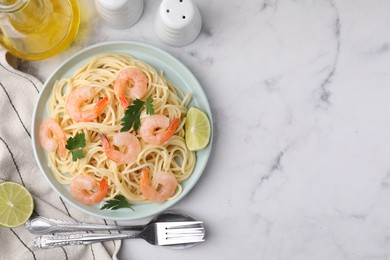 Tasty spaghetti with shrimps, lime and parsley served on white marble table, flat lay. Space for text