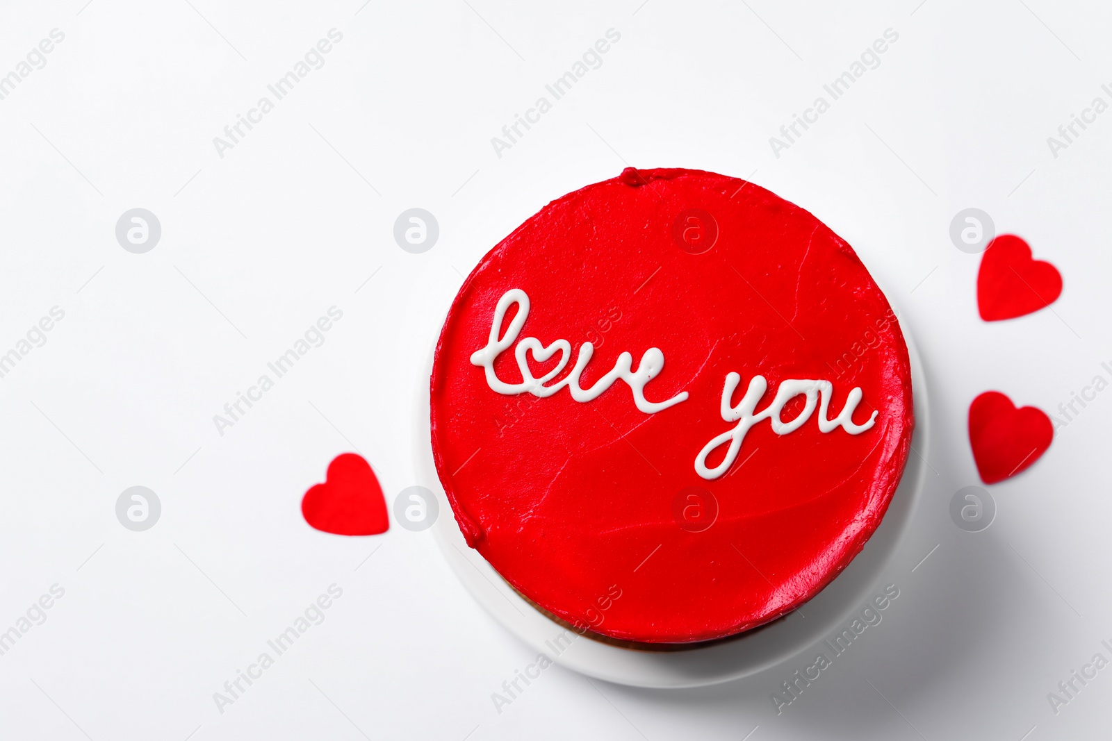 Photo of Bento cake with text Love You and paper hearts on white background, top view. St. Valentine's day surprise